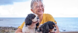 Senior woman hugging her cavalier King Charles dogs