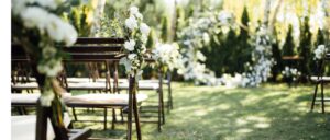 Wooden chairs decorated with flowers for an outdoor wedding ceremony