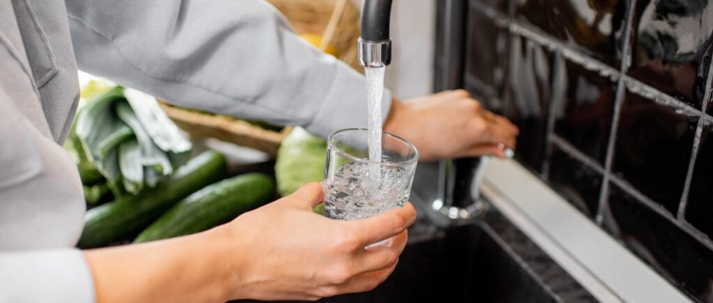 Person filling glass of water from sink.