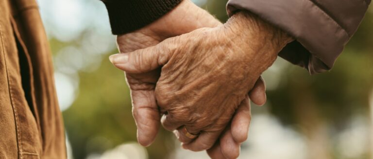 Elderly couple holding hands and walking